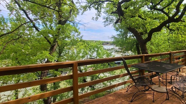 Une terrasse en bois avec une table et des chaises donnant sur une rivière.
