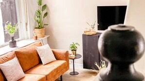 A modern living room with a leather sofa, two potted plants, a small side table, and a black vase. - Cozy home St. Philipsland with 2 bathr. (business) (Sint Philipsland)