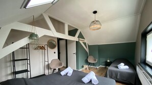 A modern bedroom with two beds, a skylight, a hanging light fixture, and a view of the outdoors. - Cozy home St. Philipsland with 2 bathr. (business) (Sint Philipsland)