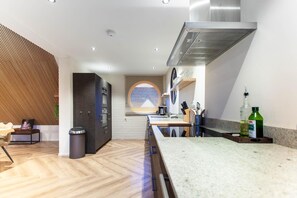 A modern kitchen with a herringbone floor, a built-in oven, and a stainless steel range hood.
