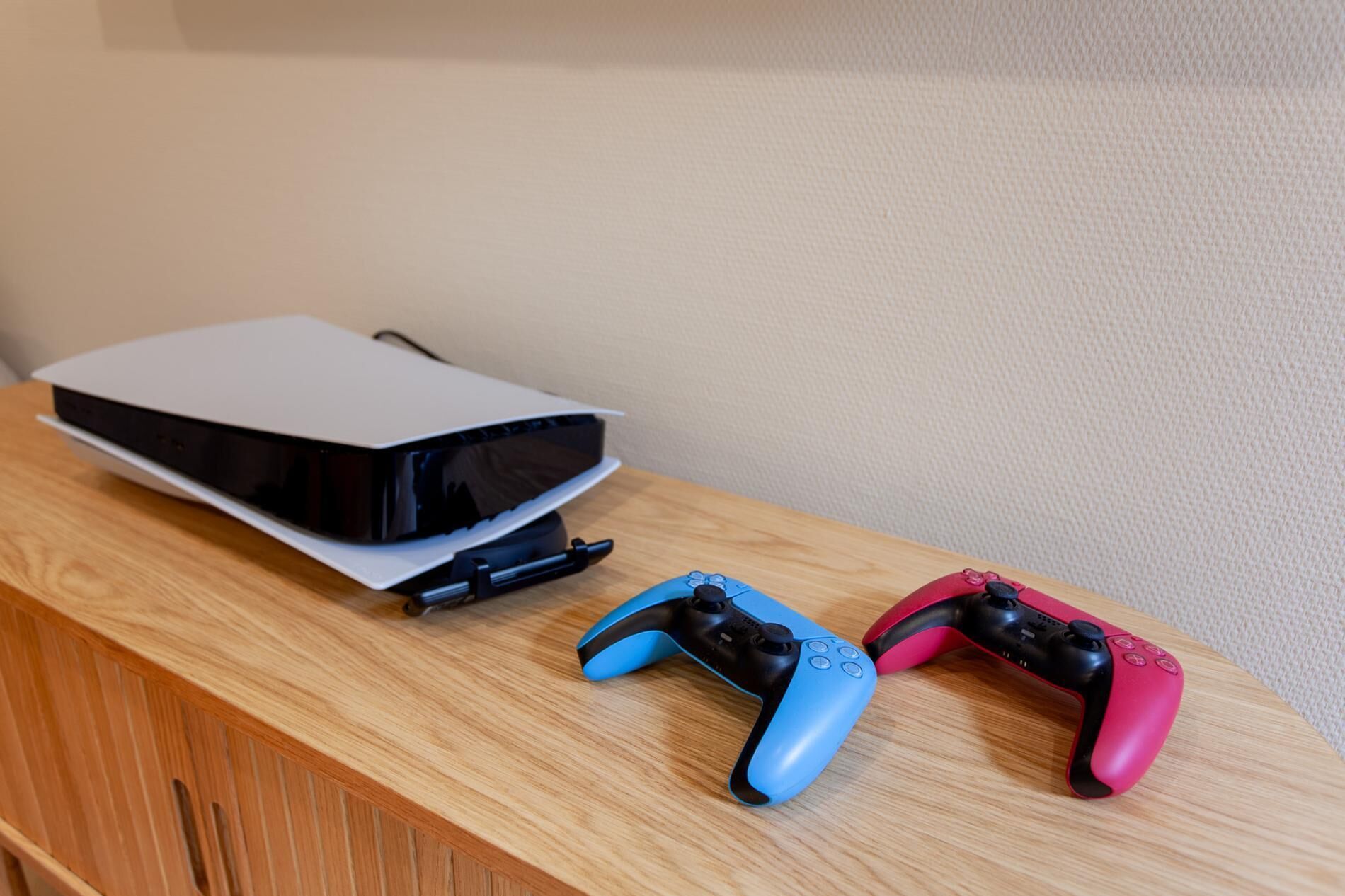 Ein Holztisch mit einer Spielkonsole und zwei Controllern.
