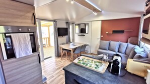 Un espacio habitable compacto con kitchenette, zona de comedor, sala de estar con sofá y televisor.