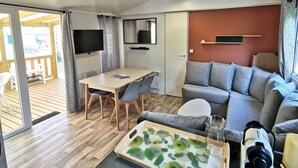 Una sala de estar moderna con un sofá, una mesa de centro, un televisor y un comedor con sillas y una mesa.