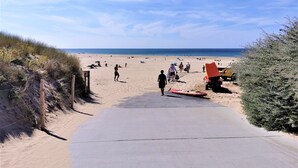 Una playa con un camino pavimentado que conduce al agua, rodeada de vegetación.