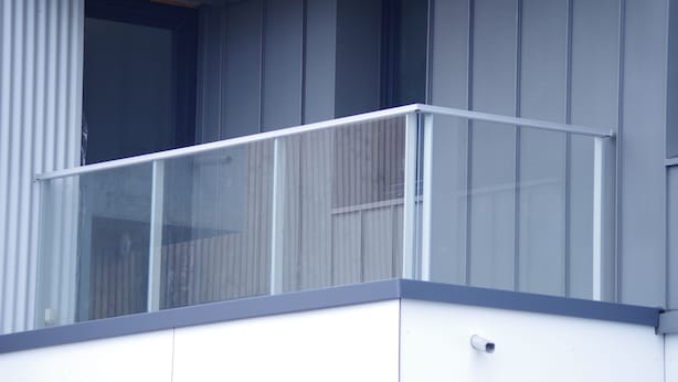 Un edificio moderno con balcón, ventanas amplias y techo de madera.