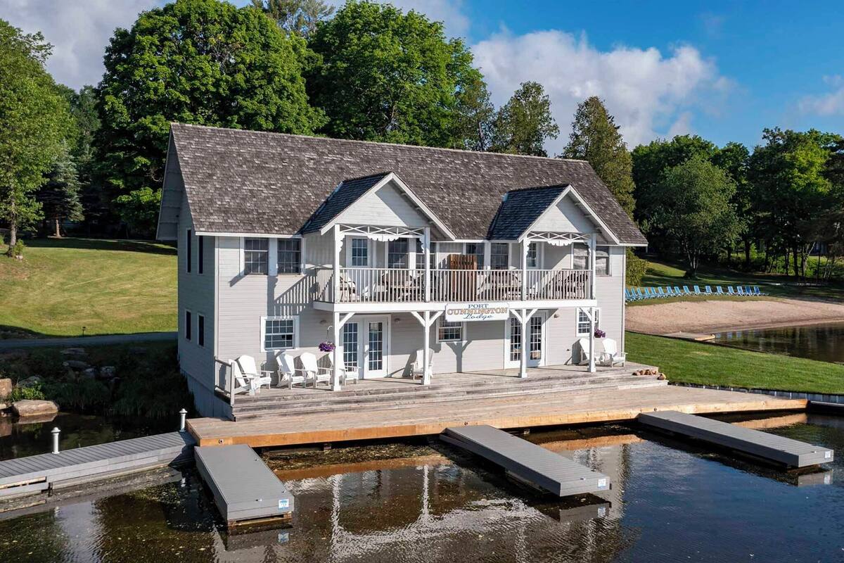 A large, two-story waterfront property with a dock extending into a lake.