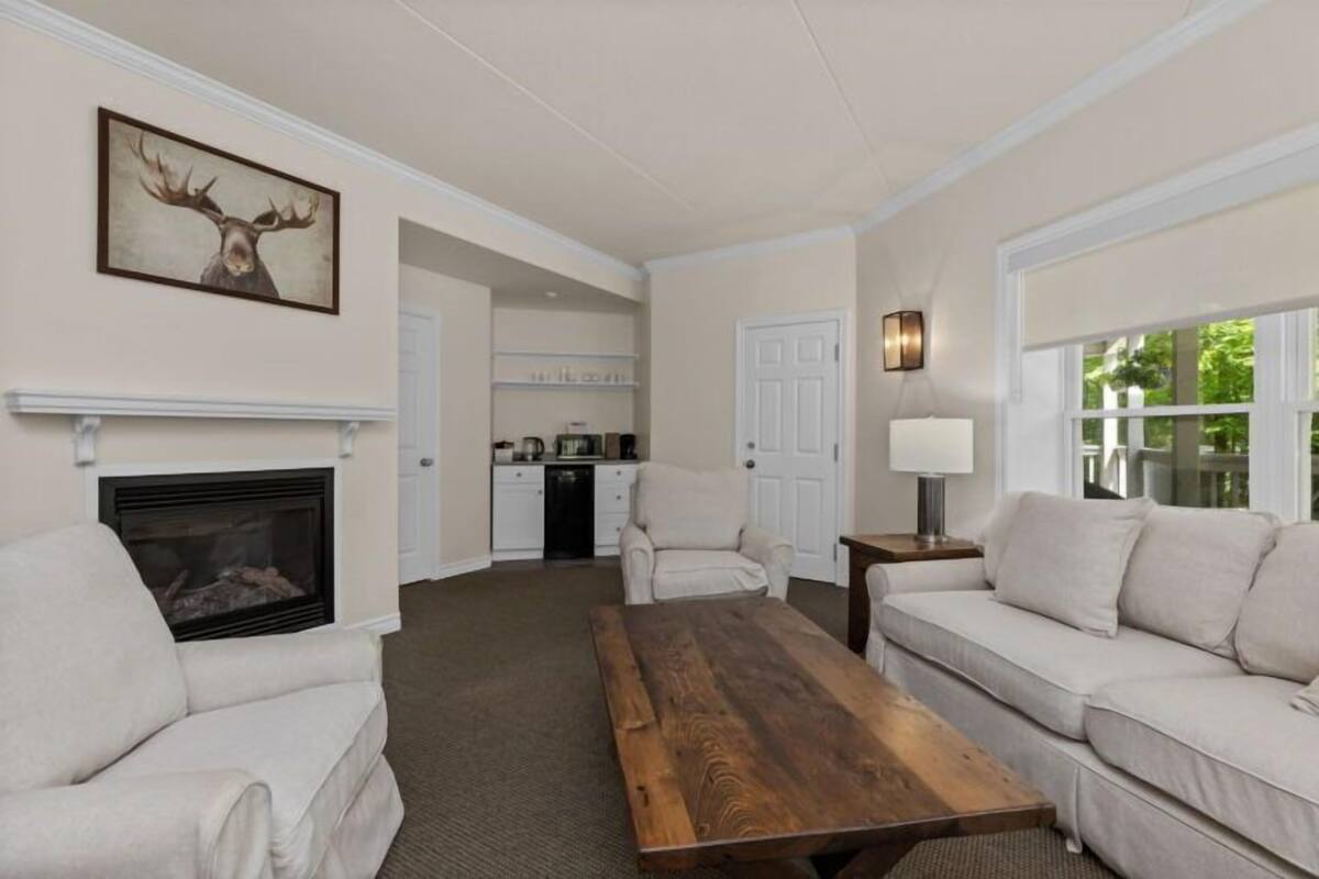 A living room with a fireplace, a wooden coffee table, a sofa, and a dining table.