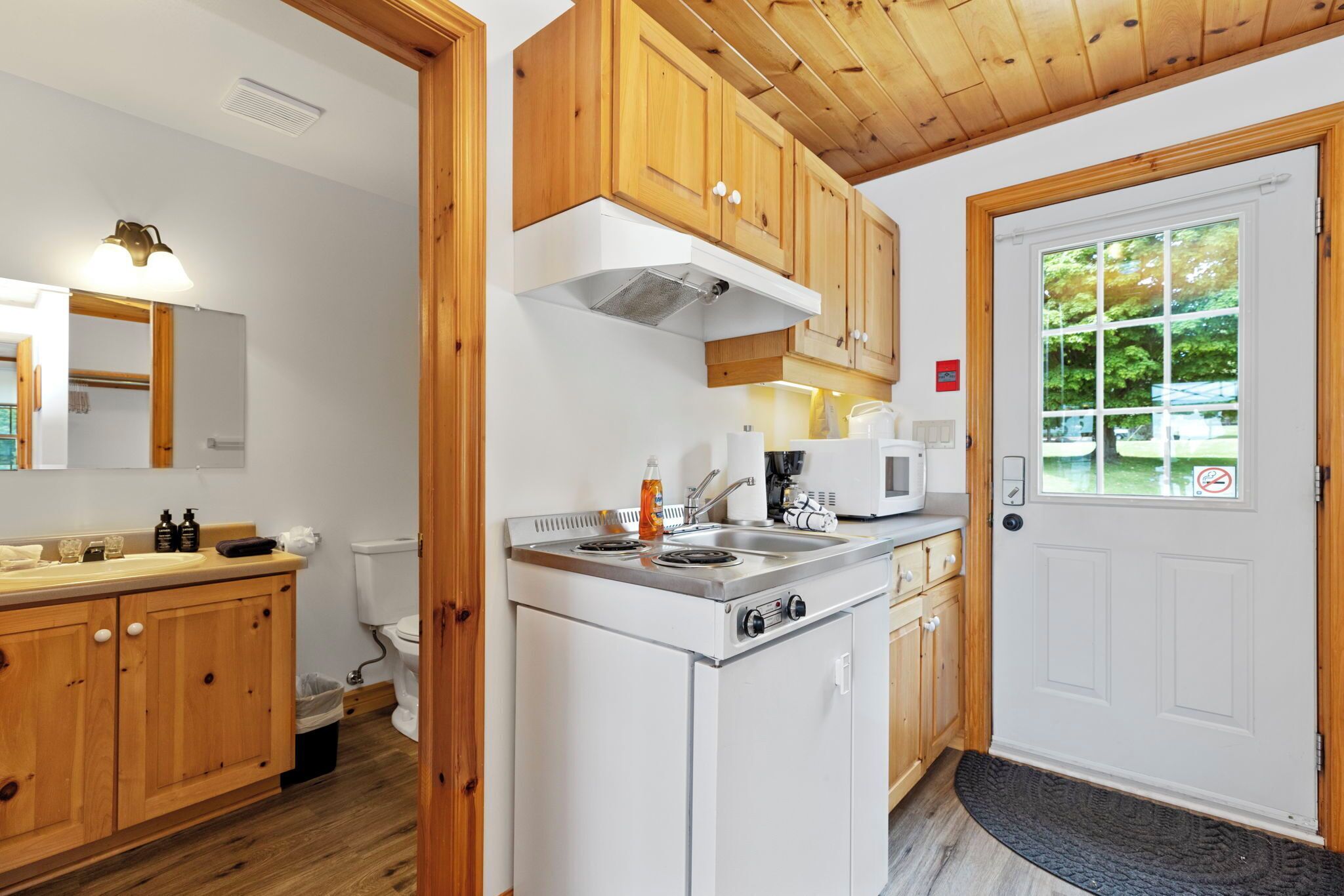 Une cuisine compacte avec des meubles en bois, une cuisinière encastrée et un four à micro-ondes.