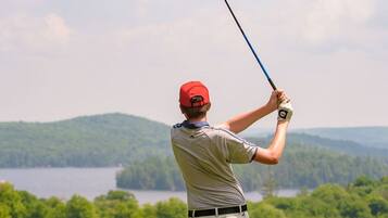 Golfers can enjoy a serene round on this well-maintained course surrounded by lush hills and a body of water.