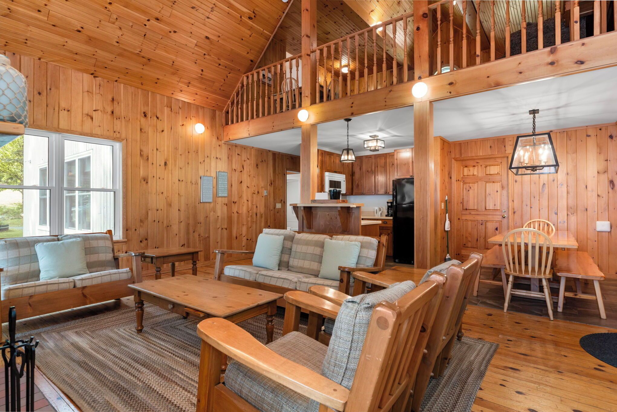 A wooden cabin interior with a living room, dining area, and kitchen.