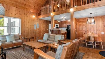 A wooden cabin interior with a living room, dining area, and kitchen.