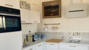 A kitchen with white cabinets, a built-in oven, a sink, and a painting on the wall.