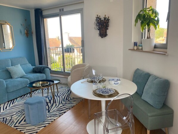 Un salon moderne avec un canapé bleu, une table ronde blanche et un canapé vert.