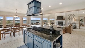 A spacious kitchen with a large island, a dining area with wooden furniture, and a view of the ocean. - Lake Home with Private Pool, Games, Views! 100 yds to Marina w boat launch! (Strawn)