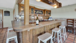 A bar area with wooden cabinets, a bar counter, and stools. - Lake Home with Private Pool, Games, Views! 100 yds to Marina w boat launch! (Strawn)