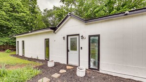 Un bâtiment blanc avec un toit noir, une porte d’entrée et deux fenêtres.