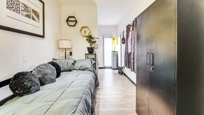 Une chambre à coucher comprenant un lit, des oreillers, une armoire et un couloir menant à une porte.