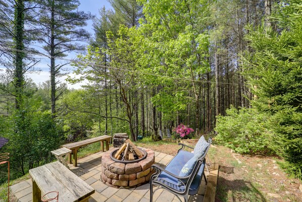An outdoor patio with a fire pit, wooden benches, and a lounge chair. - West Jefferson Vacation Rental Near River (West Jefferson)