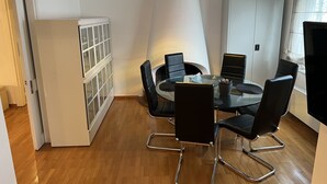 Ein moderner Essbereich mit einem Glastisch, schwarzen Stühlen und einem weißen Schrank mit Glastüren.