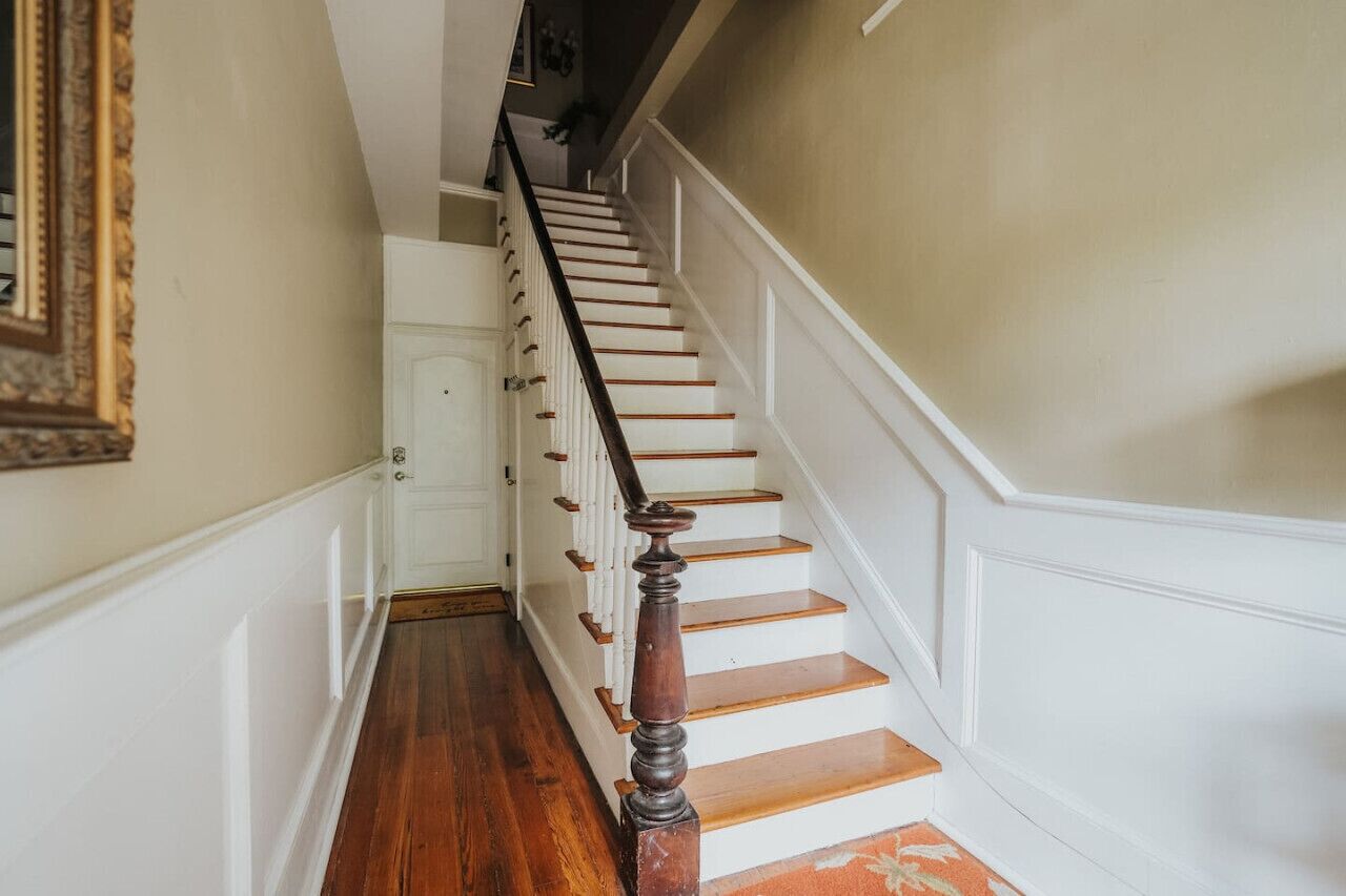 A staircase with wooden steps and a dark wooden handrail, leading to a white door at the top.