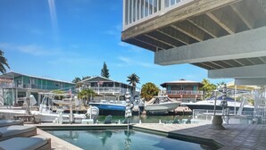 Ein Yachthafen mit vertäuten Booten, ein Schwimmbad und ein Gebäude mit einem Balkon mit Blick auf das Wasser.