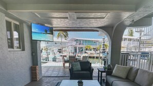 Ein Zimmer mit Fernseher, einer Couch, einem Couchtisch und Blick auf einen Yachthafen.