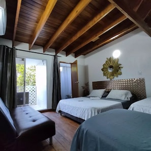 A bedroom with a wooden ceiling, a bed with a headboard, a bench, and a window with curtains.