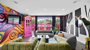 Un espace de détente moderne agrémenté d’œuvres d’art colorées sur les murs, d’une cabine téléphonique rose et d’un ensemble de canapés.