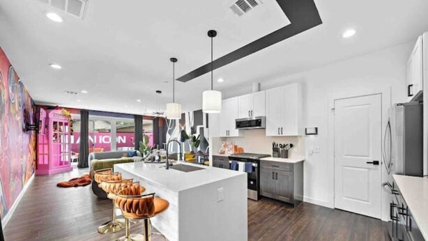 Une cuisine moderne avec des meubles blancs, un îlot central et des tabourets de bar.
