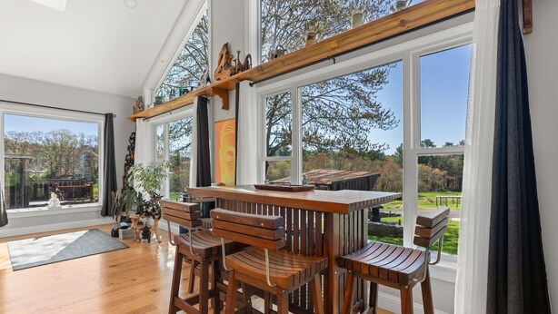 Habitación amplia con ventanas grandes, una mesa de madera con sillas y vistas al exterior.