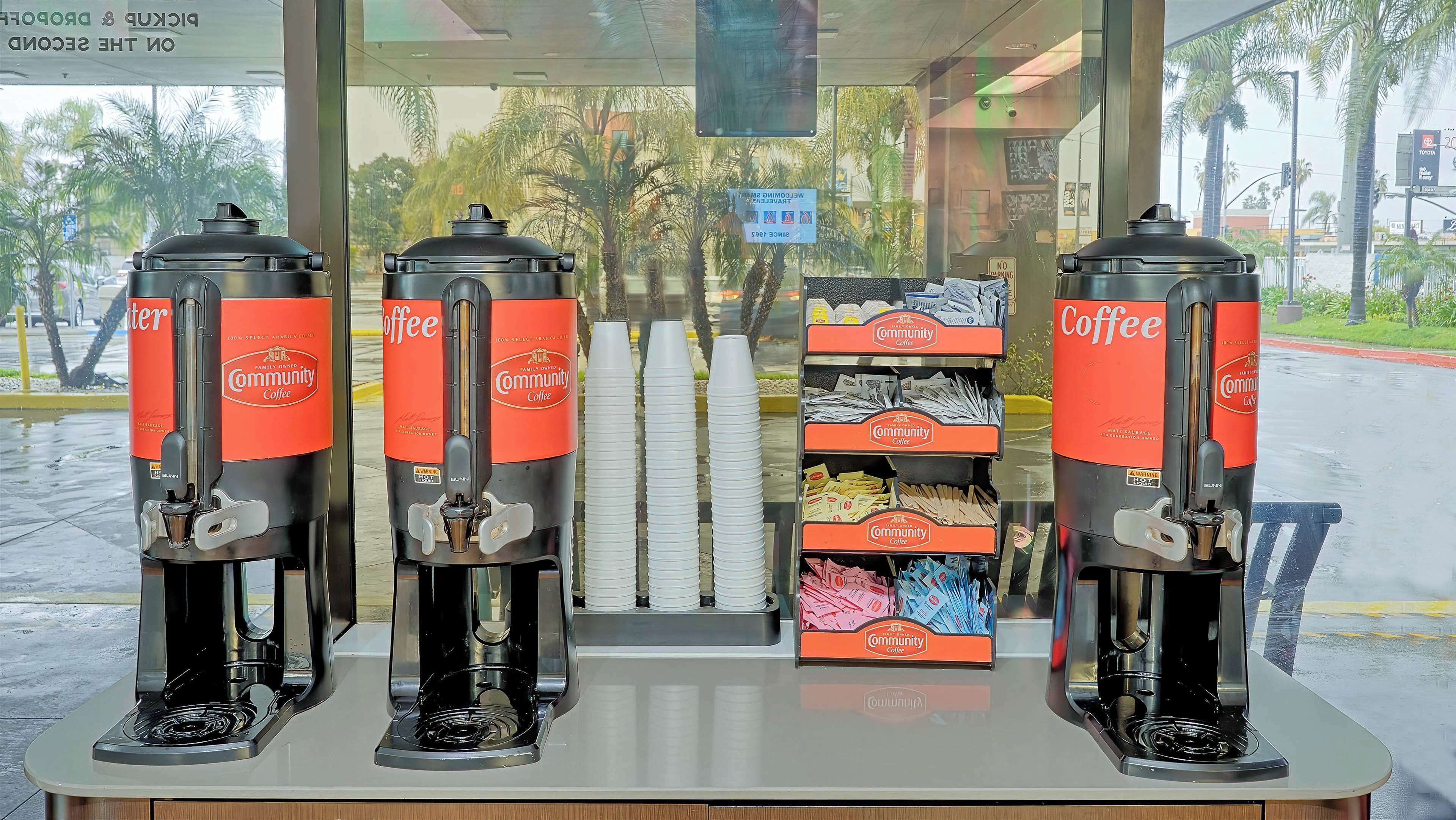 Four coffee dispensers labeled 'Community Coffee' with a sign indicating 'Welcome, please use the back door' and 'No parking'.