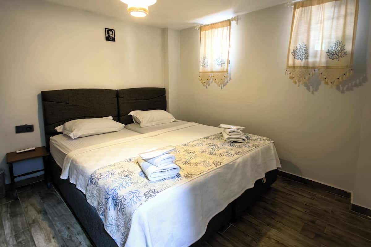 A hotel room with a large bed, a bedside table, a nightstand, and a ceiling light.