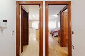 A hallway leading to a bedroom with a bed, a bedside table, and a wardrobe.