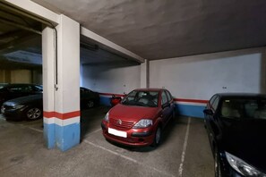 A parking garage with concrete pillars, a red car, and a black car parked. - 174A Apartment in San Lorenzo by R2R Consulting (Gijón)