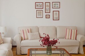 A living room with a sofa, a coffee table, and a vase with flowers. - 174A Apartment in San Lorenzo by R2R Consulting (Gijón)