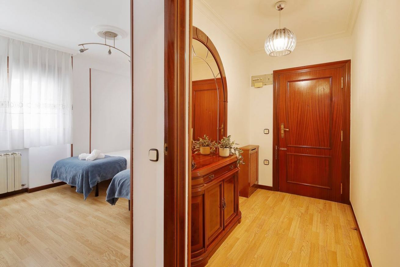 Une chambre d’hôtel avec un plancher en bois, un lit recouvert d’une couverture bleue, une armoire en bois et un miroir au-dessus de la porte.