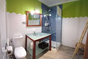 A bathroom with a toilet, sink, mirror, and shower.