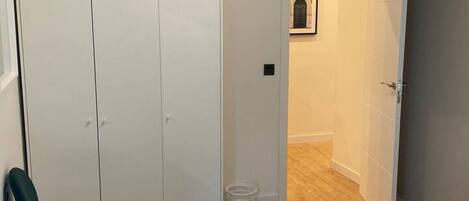 A room with a wardrobe, a chair, and a door leading to another room.