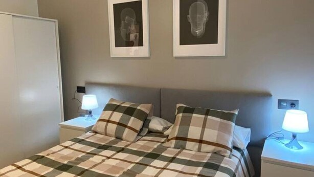 Ein Schlafzimmer mit einem Bett, zwei Nachttischen, einem Kopfteil und zwei gerahmten Bildern an der Wand.