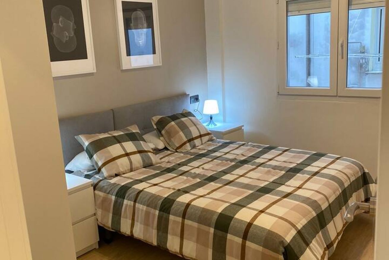 A bedroom with a bed, nightstands, a lamp, and a window.