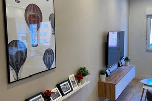 A modern living room with a mounted TV, framed pictures, and decorative plants.