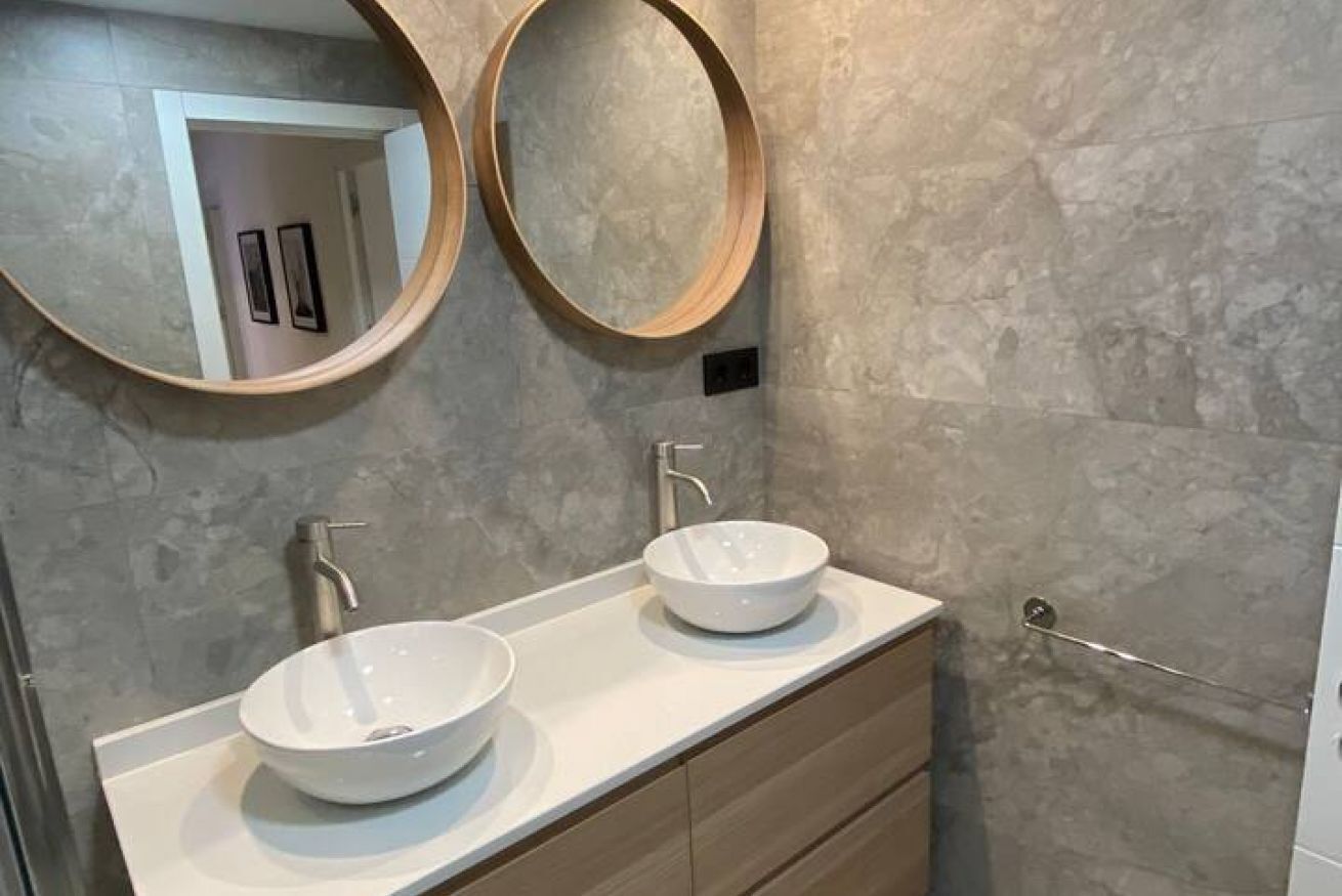 Een badkamer met twee wasbakken, een spiegel en een handdoekrek.