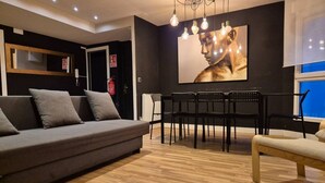 A modern living room with a sofa, dining table, chairs, and a large wall art piece. - 184A Apartment in the La Arena neighborhood by R2R (Gijón)