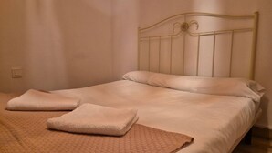 A single bed with a metal headboard, a beige blanket, and two folded towels. - 184A Apartment in the La Arena neighborhood by R2R (Gijón)