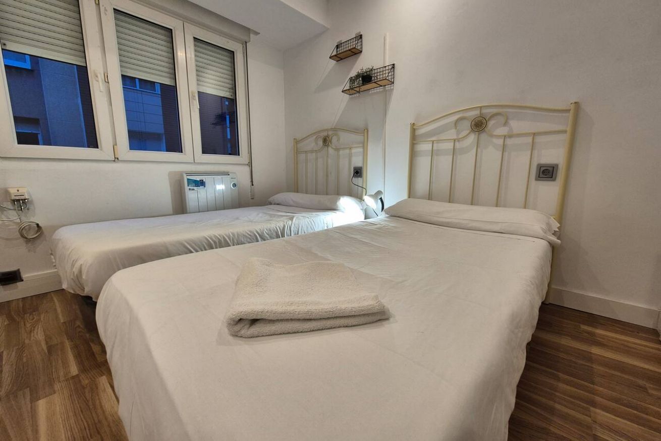A bedroom with two beds, a window, and a radiator.
