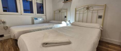 A bedroom with two beds, a window, and a radiator.
