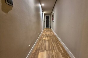 Un pasillo con piso de madera, paredes beige e iluminación empotrada.