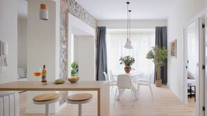 Eine moderne Küche mit einer zentralen Kochinsel, weißen Barhocker und einem Essbereich mit weißem Tisch und Stühlen.