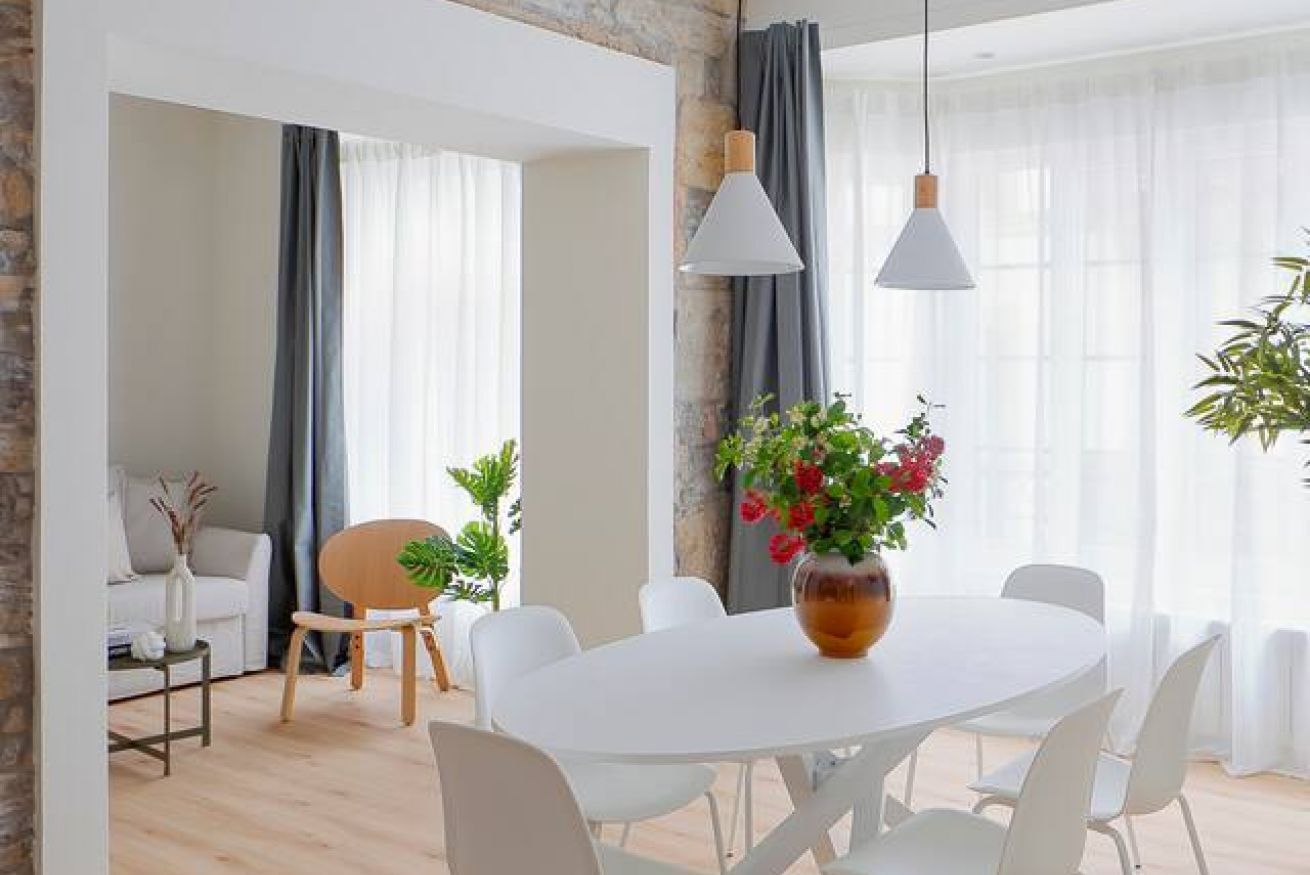 Un salon moderne avec une table à manger, des chaises blanches, un canapé et une table basse.