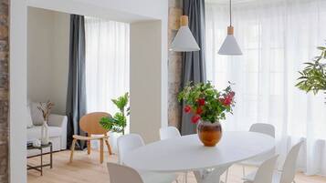 Een moderne woonkamer met een eettafel, witte stoelen, een bank en een salontafel.